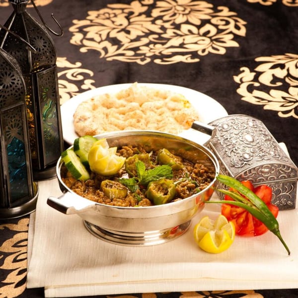 A silver bowl of Mediterranean stuffed peppers and minced meat, with naan bread and lanterns.